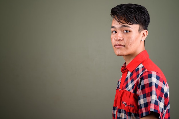 Studio shot of young teenage man wearing red checkered shirt against colored