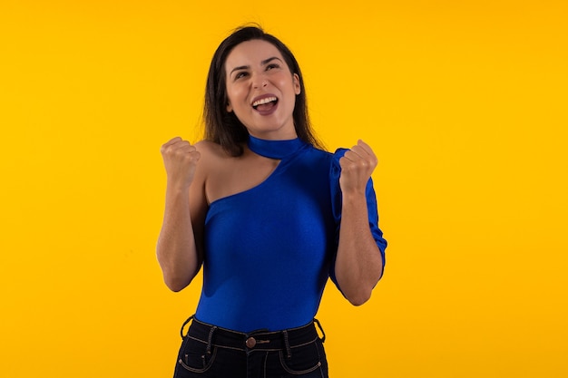 Studio shot of young woman in glasses with blue blouse on yellow background with various facial expr