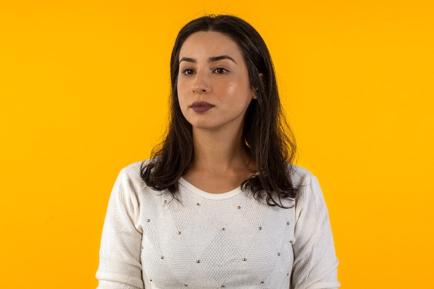 Studio shot of young woman in white shirt on yellow background with various facial expressions