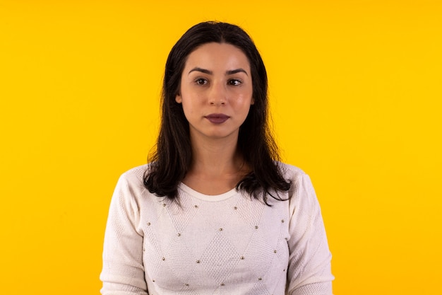 Studio shot of young woman in white shirt on yellow background with various facial expressions