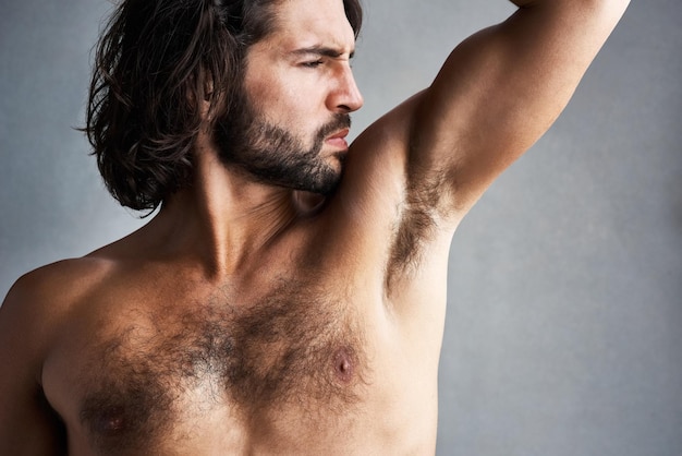 Studio sweat and man smelling underarm for grooming skincare and poor hygiene in wellness treatment Stink skin and male model with strong body odor bacteria and dirty armpit on grey background