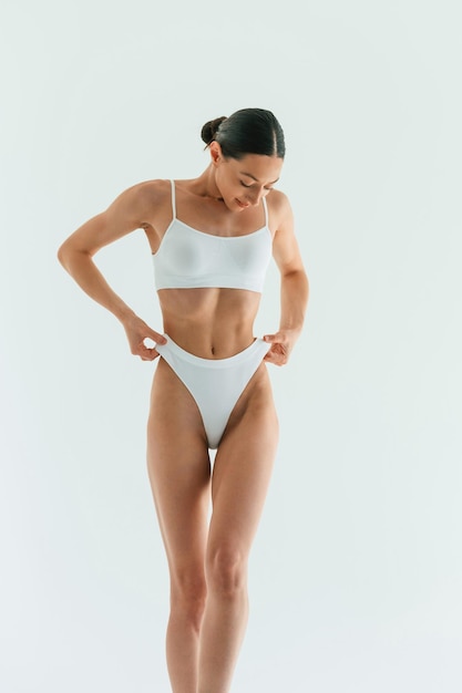 in the studio with white background young woman with slim body type is in fitness clothes
