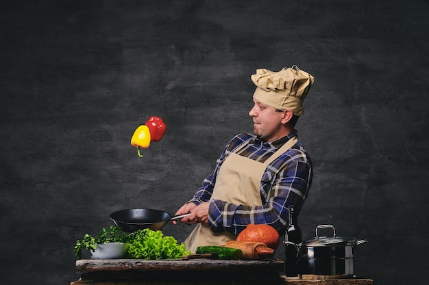 Studiobeeld van mannelijke chef-kok die maaltijden bereidt op een pan.