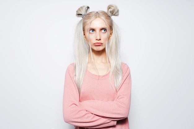 Studioportret van beledigd mooi blond meisje met twee haarbroodjes op wit