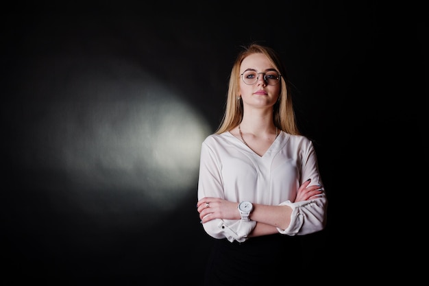 Studioportret van blonde zakenvrouw in glazen witte blouse en zwarte rok tegen een donkere achtergrond Succesvolle vrouw en stijlvol meisjesconcept