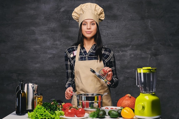 Studioportret van chef-kok vrouwelijke kok aan tafel met veel groenten.