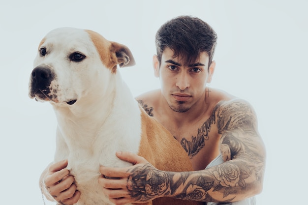 Studioportret van een jonge man met tatoeages en een hond