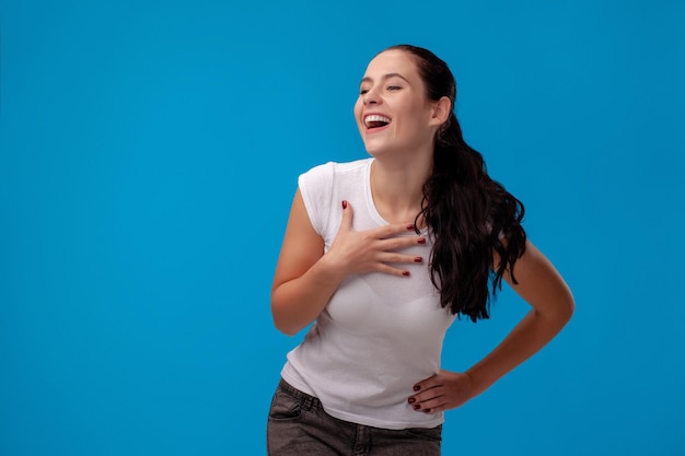 Studioportret van een jonge mooie vrouw in een wit t-shirt tegen een blauwe muurachtergrond mensen...