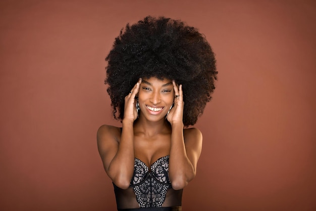 Studioportret van een mooie lachende jonge Dominicaanse vrouw met afro-kapsel