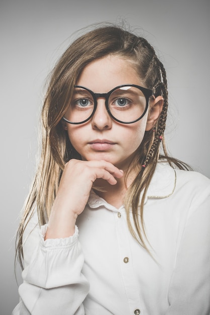 Studioportret van een schattig meisje met lang blond haar dat een bril draagt tegen een neutrale achtergrond