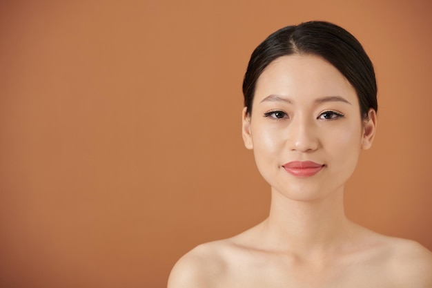 Studioportret van glimlachende jonge Vietnamese vrouw met een glimmende huid en natuurlijke make-up