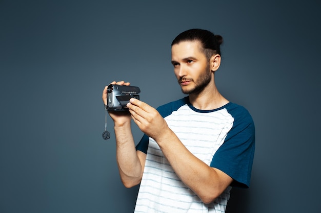 Studioportret van jonge kerel met digitale videocamera in handen