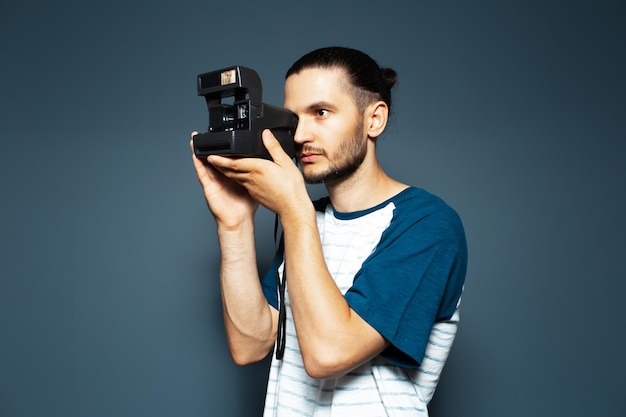 Studioportret van jonge mensenfotograaf die foto met polaroidcamera maakt