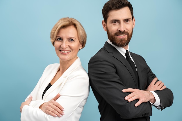 Studioportret van twee bedrijfsleider, zakenman en zakenvrouw van verschillende leeftijden, kijkend naar camera en glimlachend geïsoleerd op blauwe achtergrond