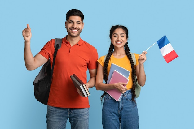 Study in france arab man and woman holding workbooks and french flag