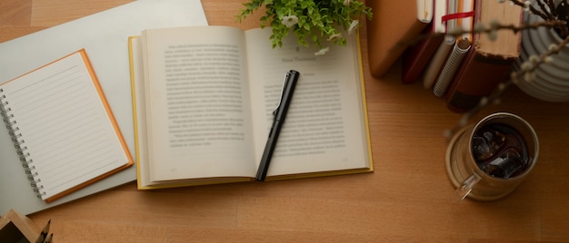 Study table with books, stationery, mock up notebook, coffee cup and decorations on wooden table