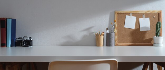 Study table with copy space, books, camera, stationery, memory board and decorations