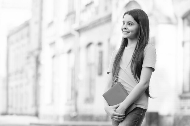 Studying of book Happy child hold school book outdors Enjoy studying Studying for exams Studying and learning Study and education School library Joyful learning copy space