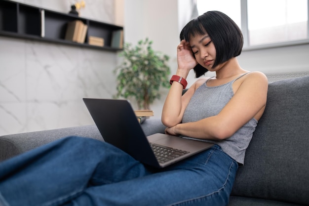 Studying. A girl sitting on the sofa with a laptop and looking busy