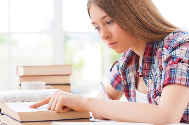 写真 猛勉強。机に座って勉強している自信を持って10代の少女の側面図