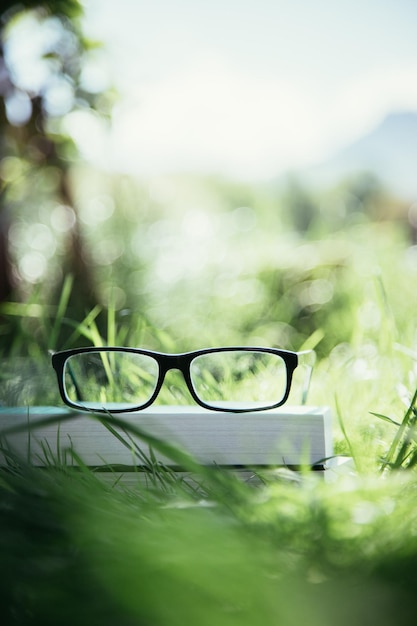 Foto studiare all'aperto bicchieri sul libro all'aperto nel parco in primavera