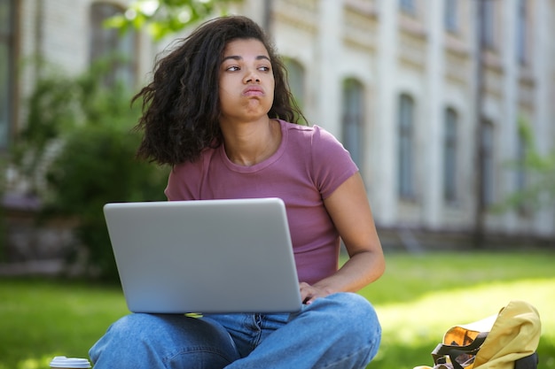 Studying in the park. a girl in a pink tshirt with a laptop in the park