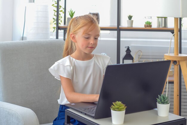 Tempo di studio una piccola studentessa interessata si siede e guarda una lezione video di istruzione