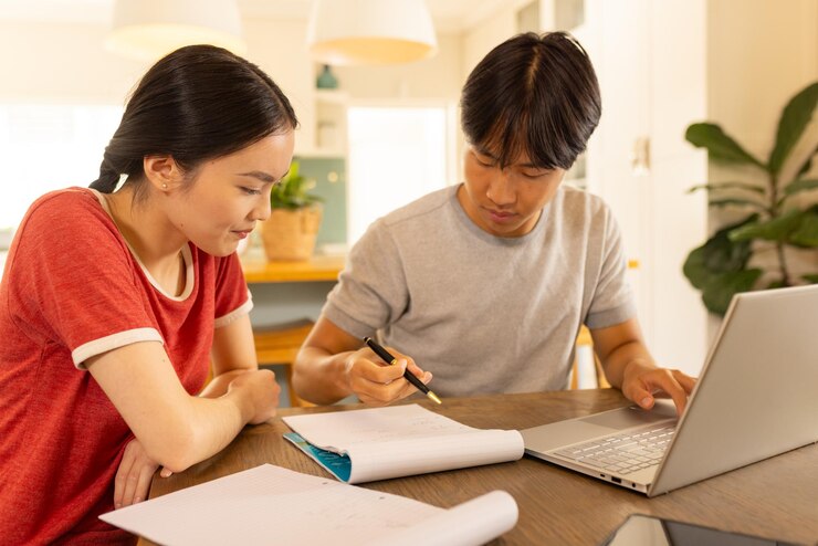アジアの若い兄弟姉妹がラップトップを使って一緒に勉強し,メモを書いています.