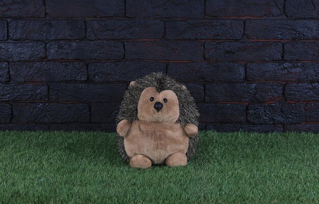 A stuffed animal sits in front of a brick wall.