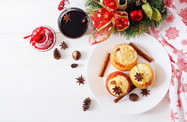 Mele al forno ripiene con ricotta, uvetta e mandorle per natale su uno sfondo bianco.