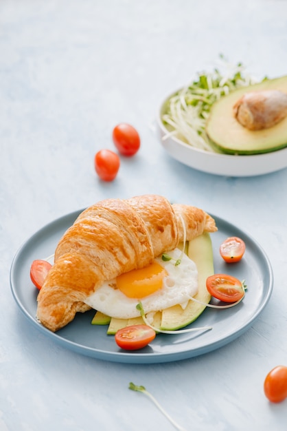 stuffed croissant with avocado, omelet egg and fresh vegetable