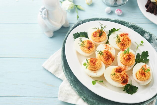 Фото Набитые или дьявольские яйца с паприкой и петрушкой на синей тарелке на пасхальный стол традиционное блюдо на пасху здоровая диетическая еда на завтрак