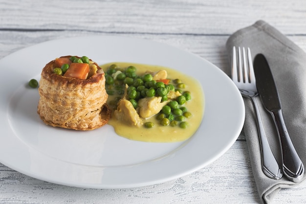 Stuffed pastry, puff pastry with chicken fricassee on a white plate, clean and aery look