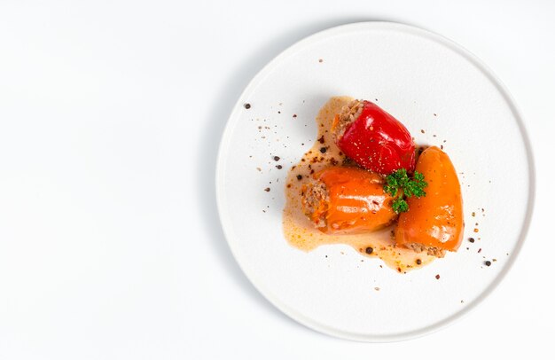 Stuffed pepper with green parsley and spices on a light surface in a white plate