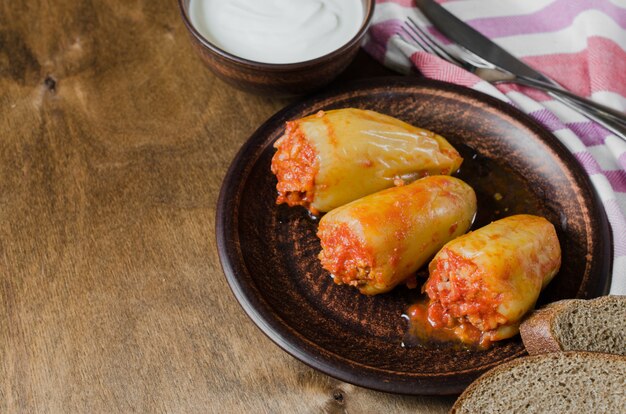 Stuffed peppers with rice and minced meat stew in tomatoes, rye bread. Rustic food.