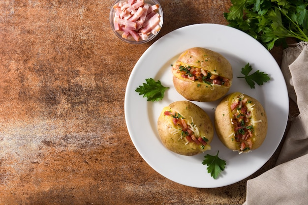 Stuffed potatoes with bacon and cheese on plate on rusty table.