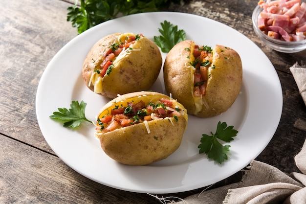 Stuffed potatoes with bacon and cheese on plate on wooden table