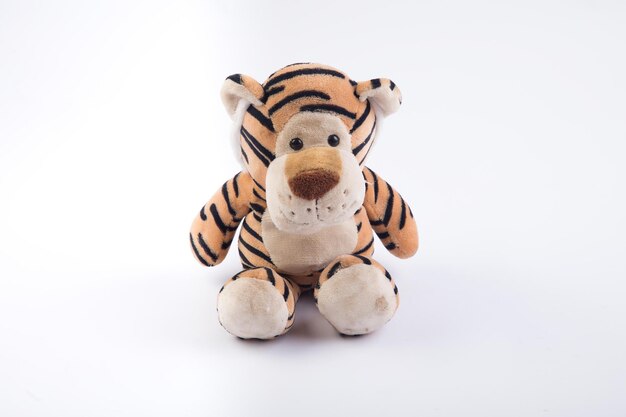 Foto un giocattolo di tigre imbottito si trova su uno sfondo bianco.