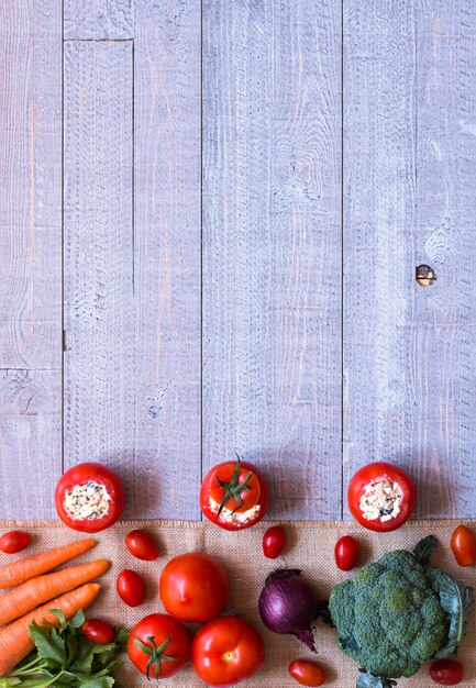 Stuffed tomatoes with cheese and different vegetables on a wooden background