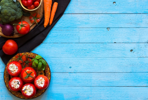 Stuffed tomatoes with cheese, and different vegetables, on a wooden background,