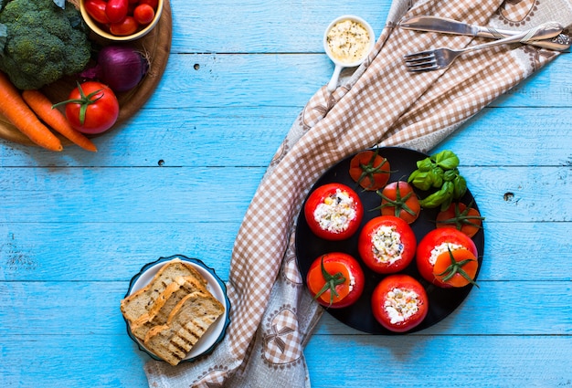 Stuffed tomatoes with cheese, and different vegetables, on wooden table