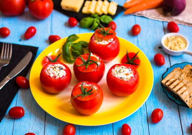 Stuffed tomatoes with cheese, and different vegetables, on wooden table