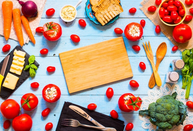 Foto pomodori ripieni con formaggio e verdure diverse su un tavolo di legno