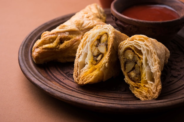 Stuffed vegetable puff or samosa, famous Indian Bakery snack, served with Tomato Ketchup and hot tea, selective focus