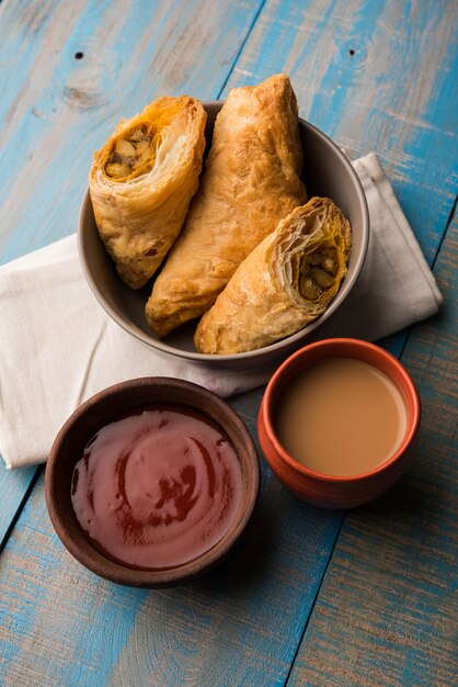 Stuffed vegetable puff or samosa, famous Indian Bakery snack, served with Tomato Ketchup and hot tea, selective focus