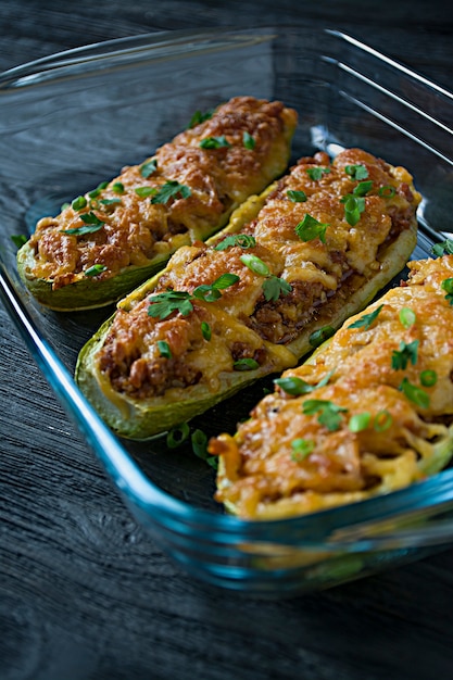 Stuffed zucchini with minced meat and grated cheese in a glass baking sheet. 