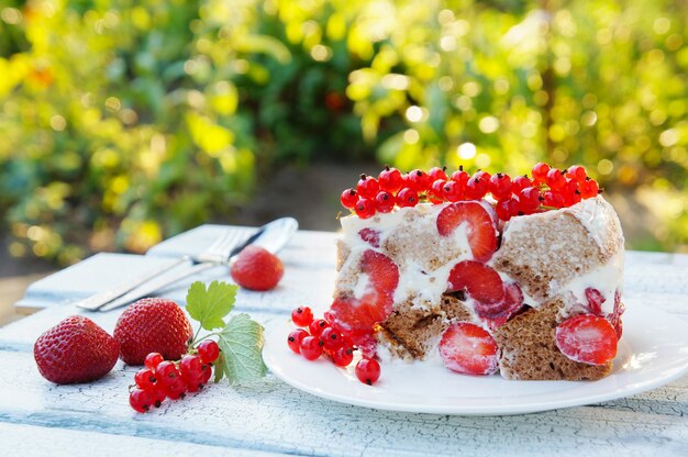 stuk chocoladekoekje cake met zure room en aardbeien op witte houten tafel