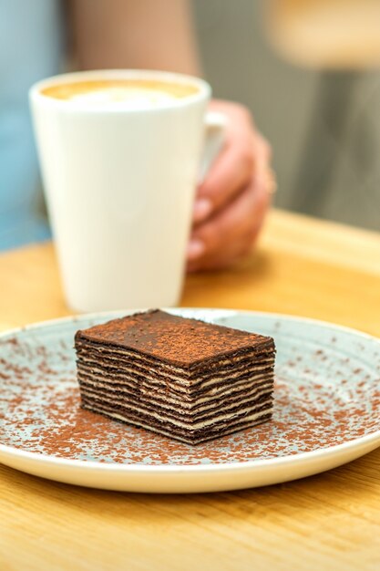 Stuk chocoladetaart op plaat met kopje koffie op de tafel in het dessertcafé