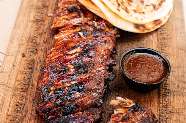 stuk gebakken vlees, gegrilde varkensribbetjes met saus en brood op een houten achtergrond