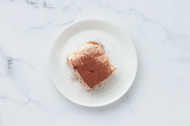 Stuk huisgemaakt Tiramisu-cakedessert op een witte marmeren achtergrond